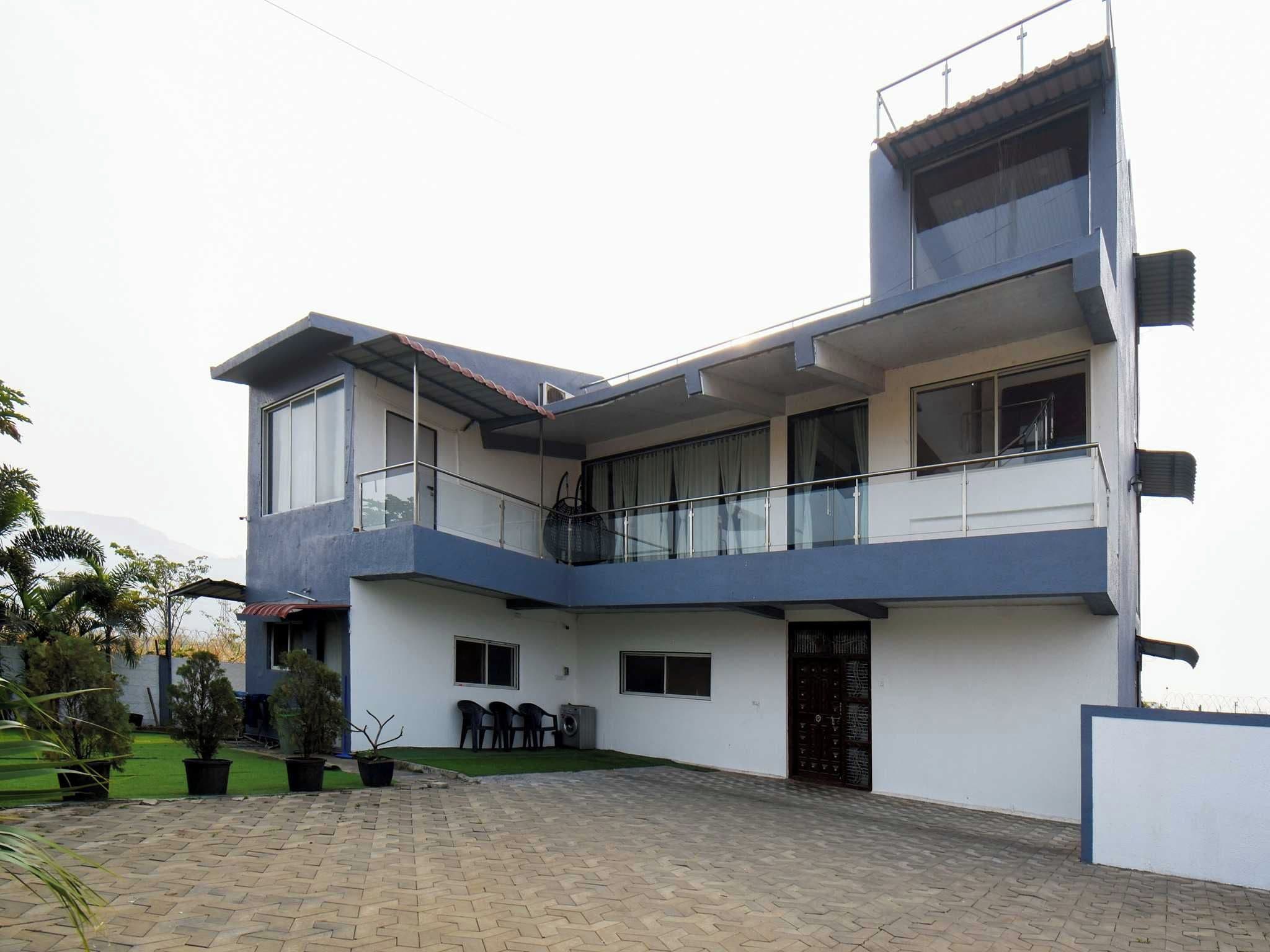 A modern two-story building with a flat roof, large windows, and a covered outdoor seating area.
