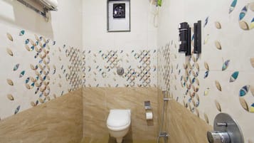 Un baño con inodoro, ducha y lavamanos empotrado.