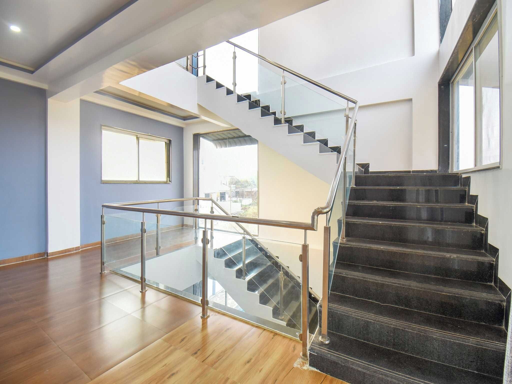 Un interior moderno con una escalera de barandilla de cristal que conduce a un nivel superior.