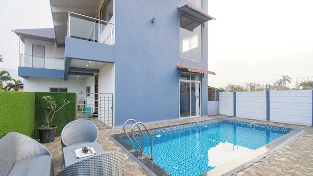 Um edifício moderno de dois andares, com piscina, área de estar ao ar livre e portão fechado.