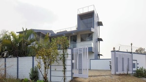 Um edifício moderno de dois andares com telhado plano, varanda e entrada com portão.