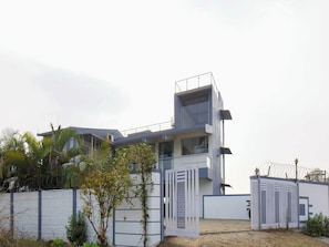 A modern two-story building with a flat roof, a balcony, and a gated entrance. - DanCenter Arohi Villa 4BHK Pvt Pool (Mawal)