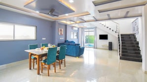 Interior moderno com área de jantar, sofá, escada e vista para o exterior.