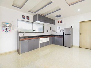 A modern kitchen with grey cabinets, a stainless steel refrigerator, and a water dispenser. - DanCenter Arohi Villa 4BHK Pvt Pool (Mawal)