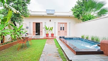 Una propiedad residencial con piscina, un sendero pavimentado y un pequeño jardín.