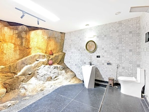 A bathroom with a rock wall mural, a sink, and a toilet. - DanCenter Parijat Villas & Suites Pool (Udaipur)
