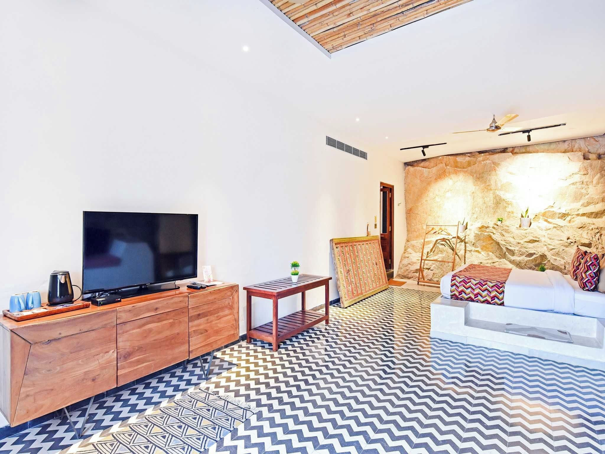 Una sala moderna con televisor, mueble de madera, piso estampado y pared de piedra.