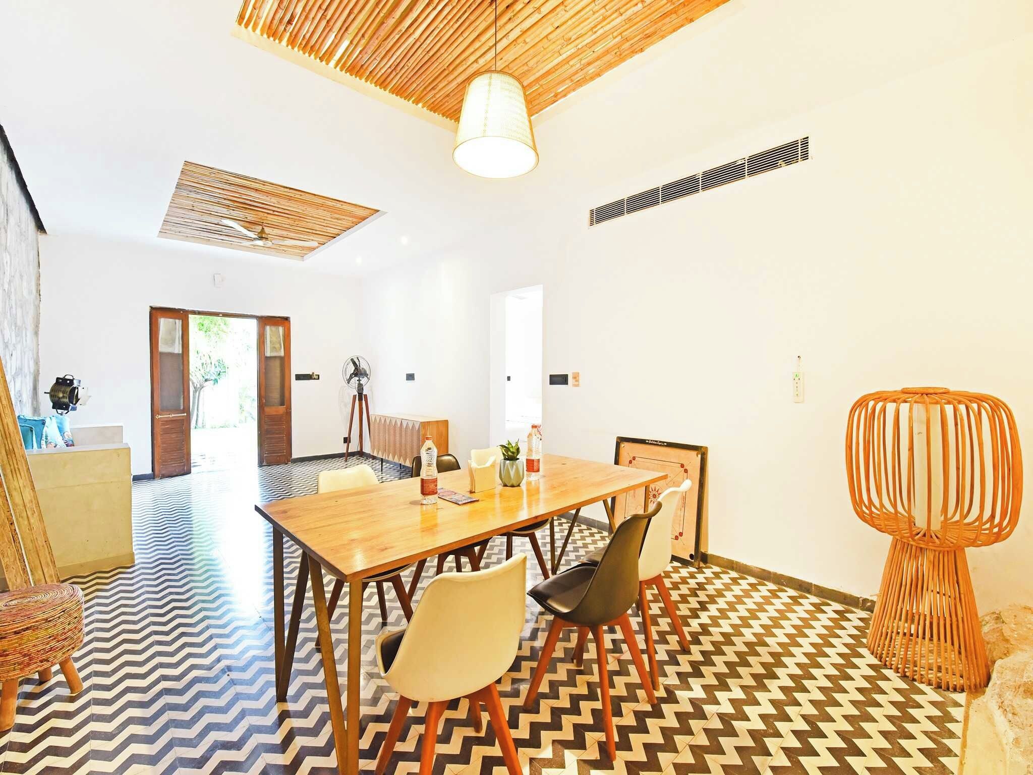 Un comedor con una mesa de madera, sillas y un suelo estampado.