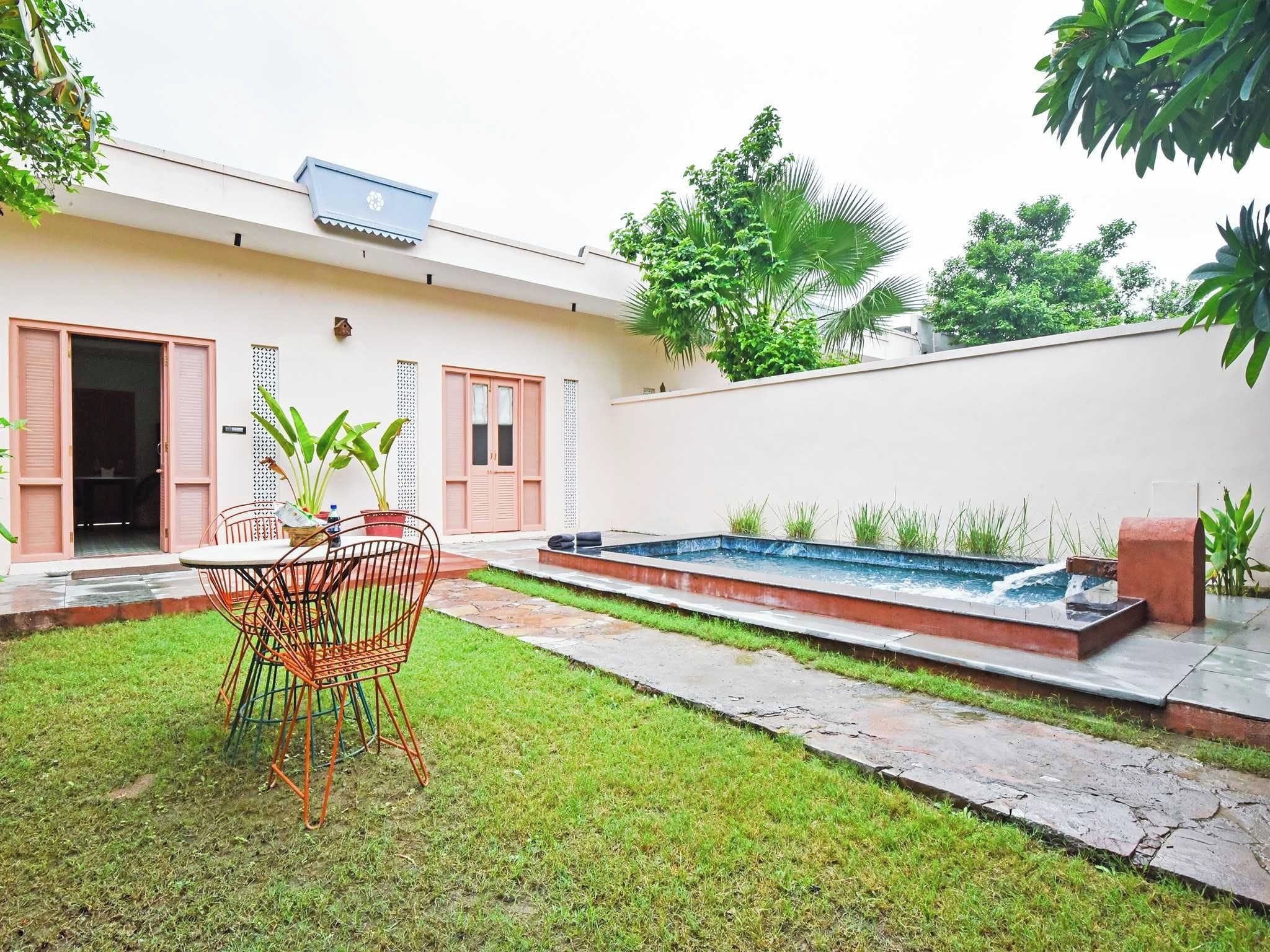 Propiedad residencial con piscina, zona de comedor con mesa y sillas, y césped bien cuidado.