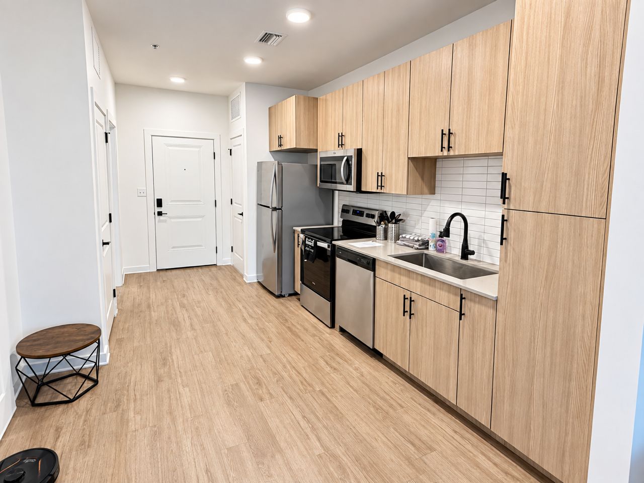 A modern kitchen with wooden cabinets, stainless steel appliances, and a white tiled backsplash.