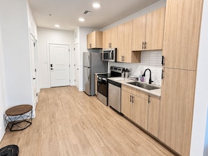 A modern kitchen with wooden cabinets, stainless steel appliances, and a white tiled backsplash.