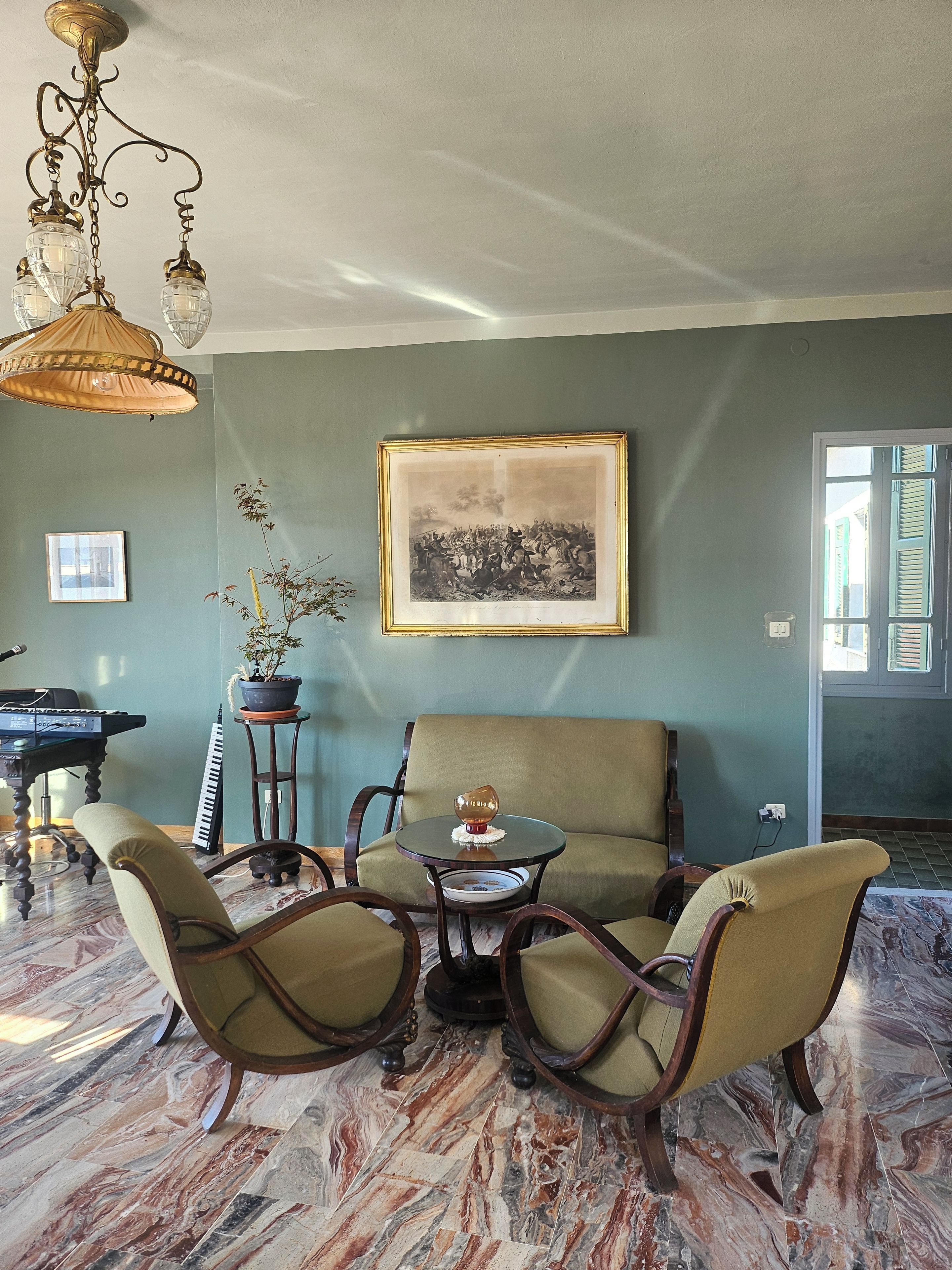 Une pièce comprenant un canapé, des fauteuils, une table, un piano et un tableau encadré accroché au mur.