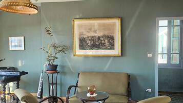 Une pièce comprenant un canapé, des fauteuils, une table, un piano et un tableau encadré accroché au mur.
