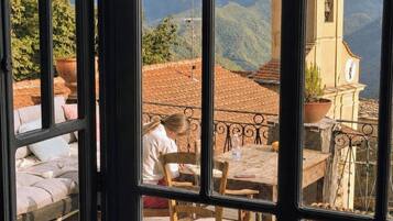 A room with a view of a mountain landscape and a church tower.