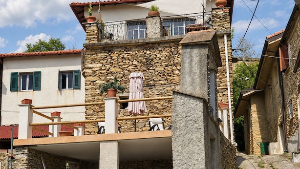 Un edificio de piedra con un balcón, una escalera y un camino empedrado.