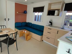 A compact living space with a sofa, a small dining table, a kitchenette, and a window. - Tranquil French Riviera Oasis (Hyères)