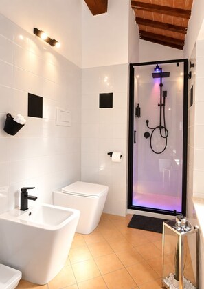 Ein modernes Badezimmer mit einer Duschkabine aus Glas, einem weißen Waschbecken und einer Toilette.