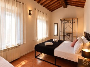 Ein Schlafzimmer mit einem Bett, einem Heizkörper, einer Wandleuchte und einem Kleiderhaken.
