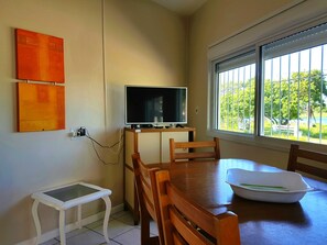 Een eethoek met een televisie op een standaard, een kleine tafel en stoelen.
