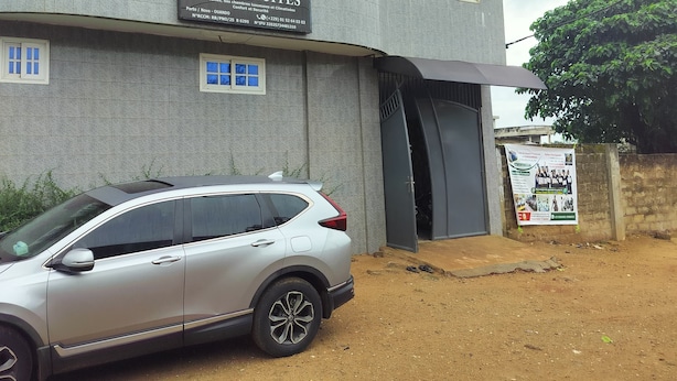 A multi-story building with a sign for 'Nivada Suites' indicating it is a hotel. There is a parked car in front. - Résidence Nivada Suite (Porto-Novo)