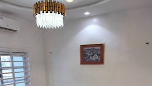 A living room with a sofa, two armchairs, a round coffee table, and a chandelier. - Résidence Nivada Suite (Porto-Novo)
