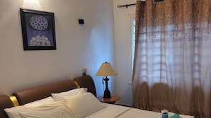 A neatly made bed with white linens, a bedside lamp, and a decorative pillow. - Résidence Nivada Suite (Porto-Novo)