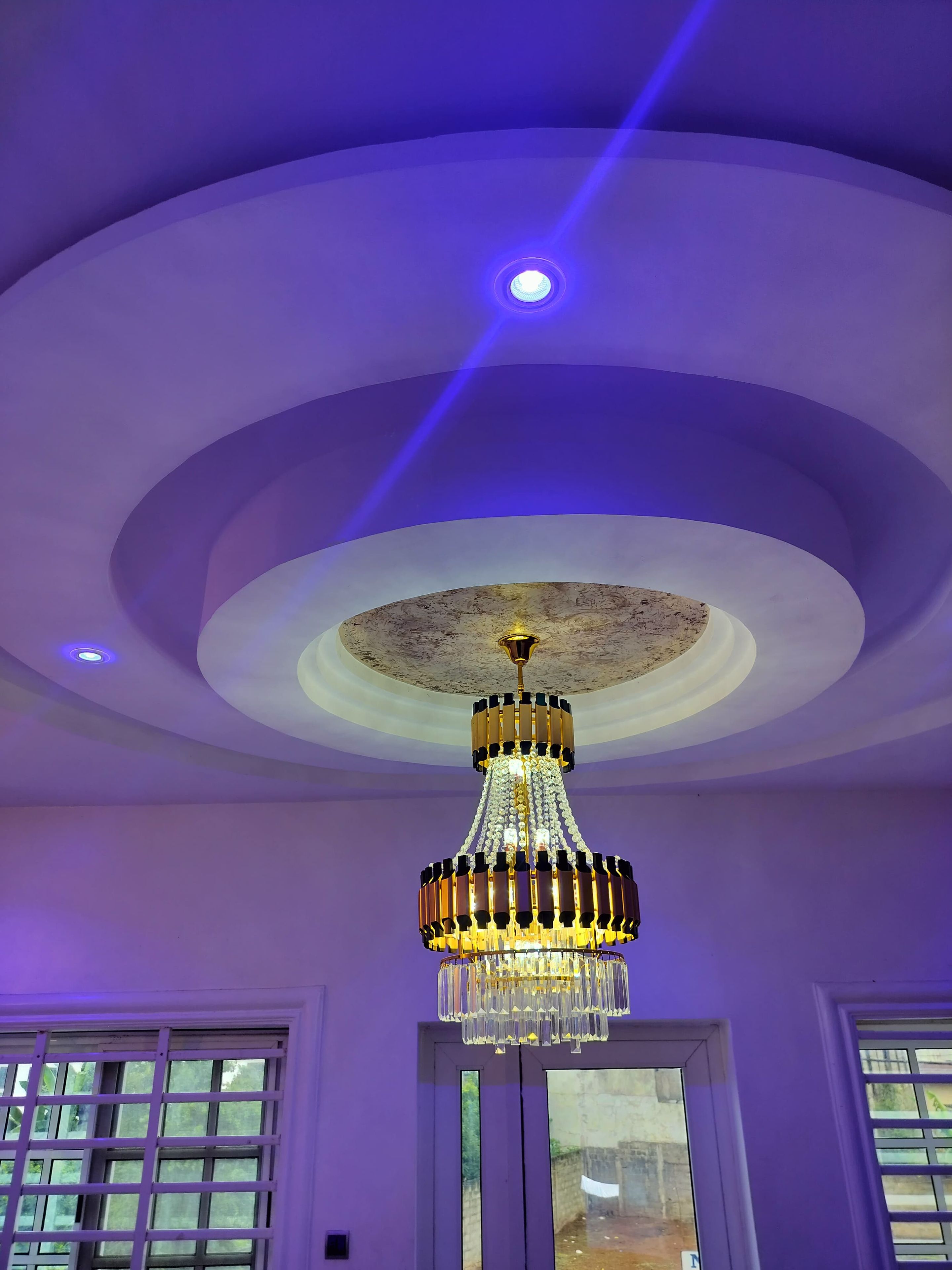 A room with a ceiling featuring a circular design and a chandelier.