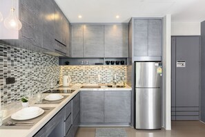 Een moderne keuken met grijze kastjes, een roestvrijstalen koelkast en een betegelde achterwand.
