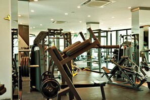 Een fitnessruimte met diverse trainingsapparaten, waaronder krachttoestellen en losse gewichten.