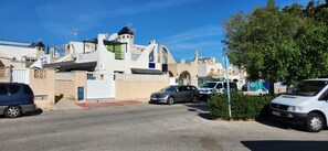 A residential street with parked cars, a white van, and a building with a unique architectural design. - House for 4–6 people in Torrevieja (Torrevieja)