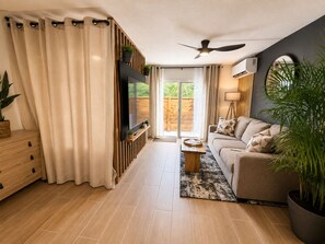 A modern living room with a sofa, TV, and a ceiling fan. - Gusto’s Inn_2 Queen Beds Sleeps 4 (Philipsburg)
