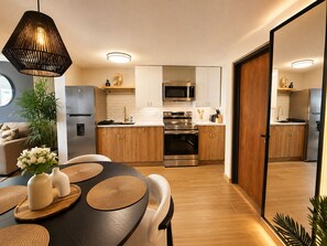 A modern kitchen with stainless steel appliances, wooden cabinets, and a dining area with a round table and chairs. - Gusto’s Inn_2 Queen Beds Sleeps 4 (Philipsburg)