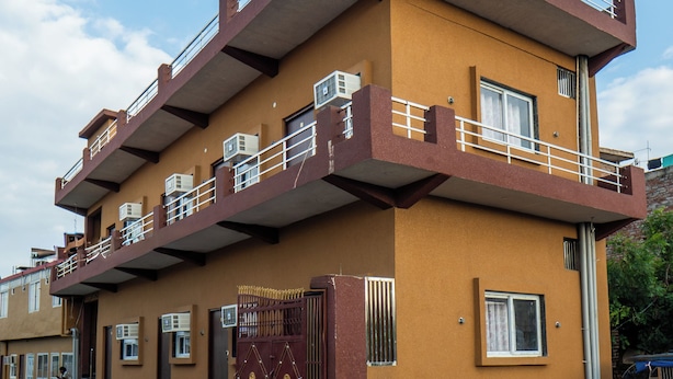 Ein zweigeschossiges Wohngebäude mit einem Balkon im oberen Stockwerk, einem verschlossenen Eingang und einem gepflasterten Auffahrt.
