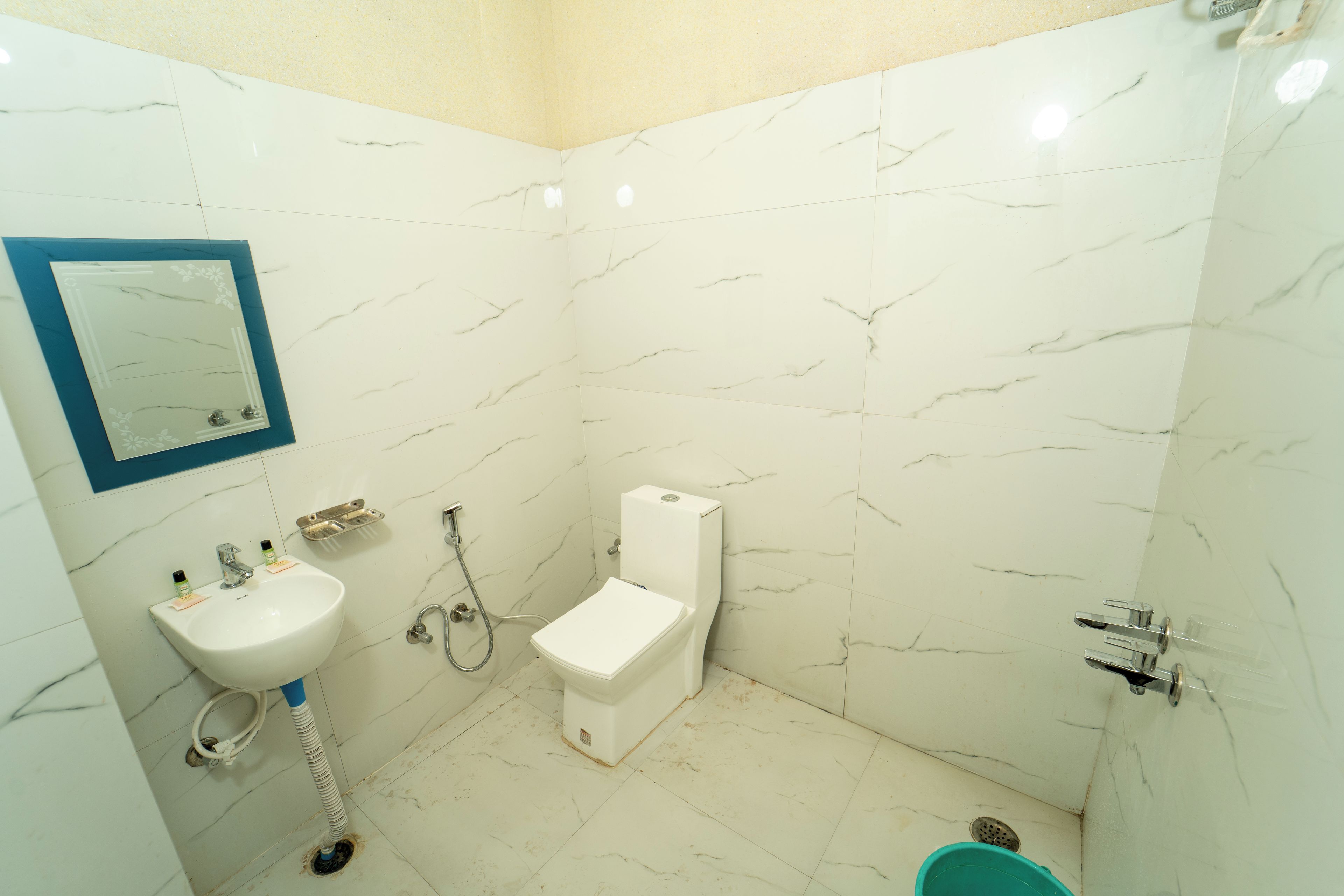 A bathroom with white marble walls, a white sink, a toilet, and a shower.