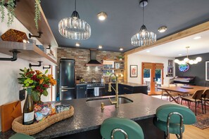 A modern kitchen with a central island, black cabinets, and stainless steel appliances. - Loft of Legends-Vinyl Lounge/Walk to UF/Hot Tub/Sleeps 10 (Gainesville)