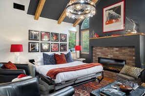 Une chambre à coucher moderne avec un lit, une cheminée et une collection de tableaux encadrés accrochés au mur.