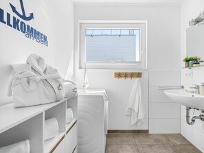 Ein modernes Badezimmer mit einem weißen Waschbecken, einer Duschkabine aus Glas und einem Handtuchhalter.