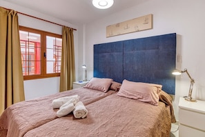 A bedroom with a large bed, a headboard, a nightstand, a lamp, and a window with curtains. - Apartamento Delphin Sol – Sea Views and Beachfront Location in Puerto Naos (Puerto de Naos)