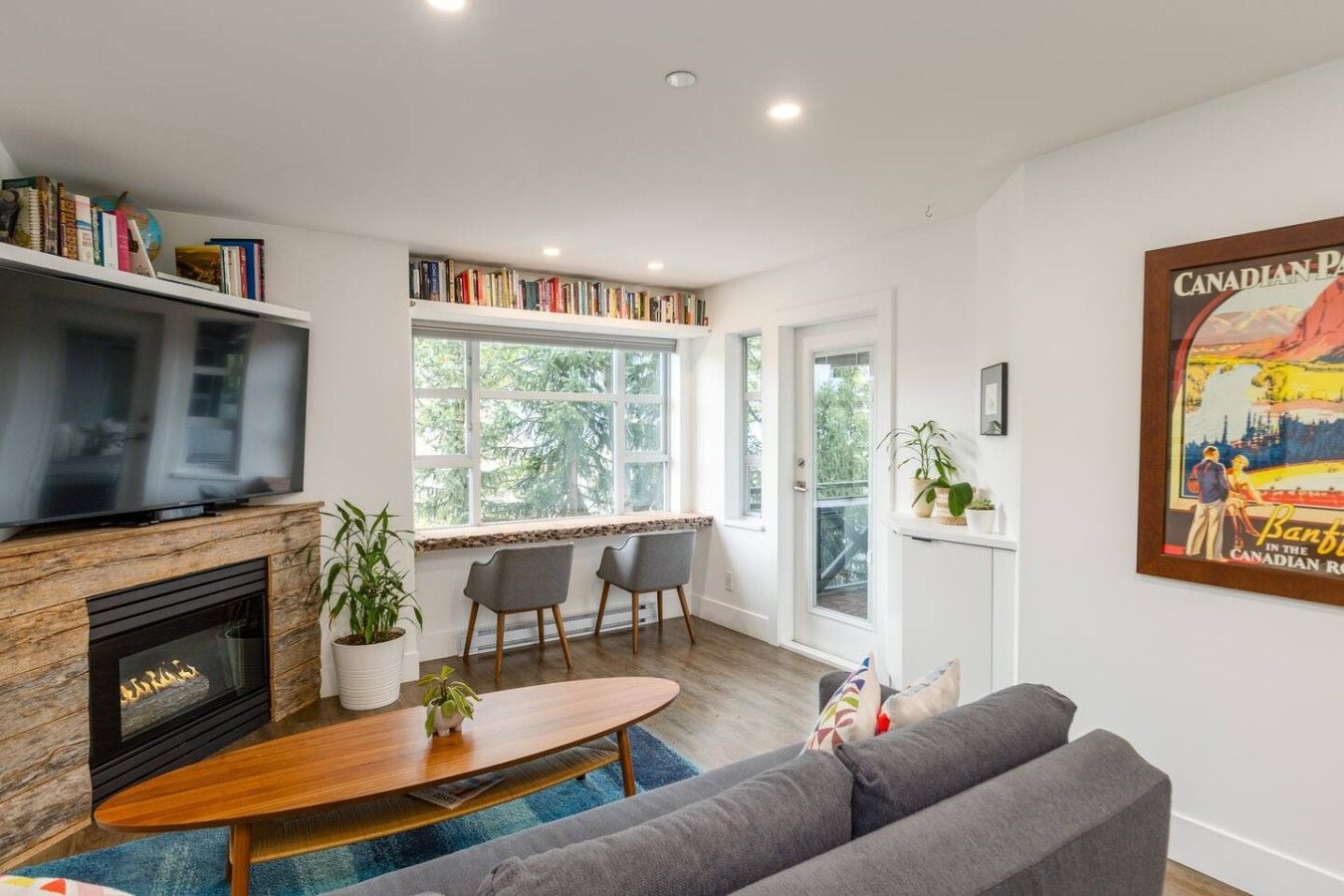 A modern living room with a fireplace, a television, a sofa, and a bookshelf.
