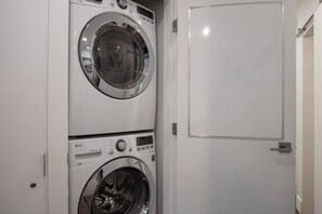 A laundry room with two stacked washing machines and a white door. - Well Appointed 2BD w/ Great Location @Marketplace (Whistler)