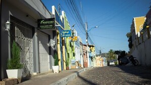 A street with a hotel named 'HOSPEDARIA' on the left, a sign for 'Bodega da Gelo' in the middle, and a motorcycle parked on the right. - Hospedaria Valdice Damasceno (Piranhas)