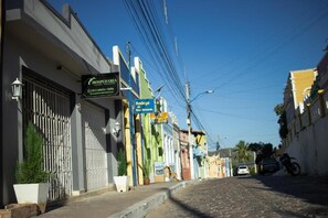 A street with a hotel named 'HOSPEDARIA' on the left, a sign for 'Bodega da Gelo' in the middle, and a motorcycle parked on the right. - Hospedaria Valdice Damasceno (Piranhas)