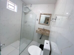A bathroom with a glass-enclosed shower, a toilet, and a sink with a marble countertop. - Hospedaria Valdice Damasceno (Piranhas)