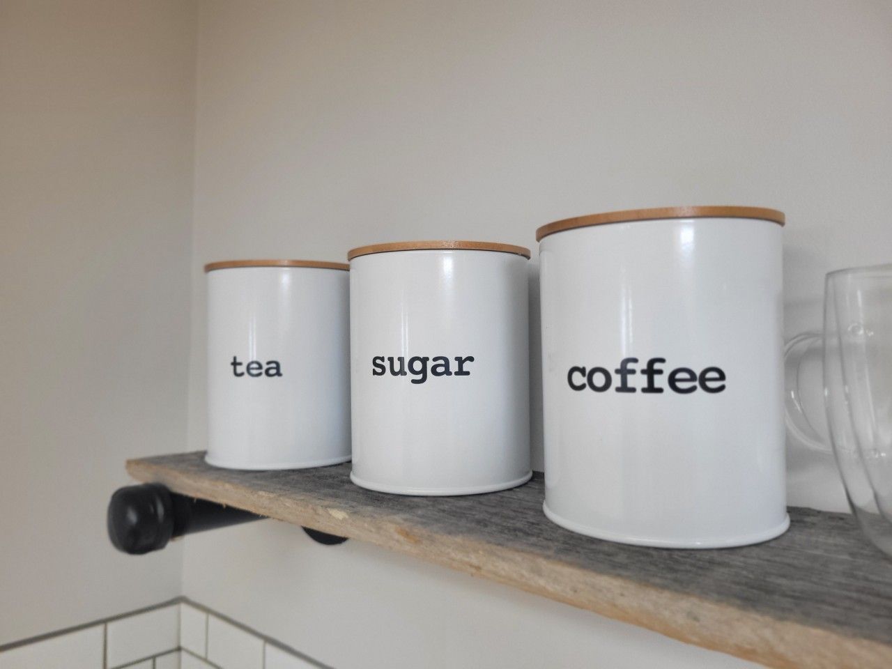 Three white containers with labels on a shelf.