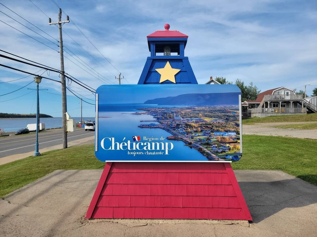 A sign with a view of a coastal town and a star on top.