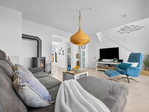 Una sala de estar moderna con chimenea, sofá, sillón y televisor.