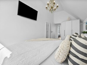 Un dormitorio con cama, televisión montada en la pared y una araña.