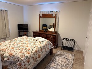 A bedroom with a bed, dresser, mirror, television, and a small rug. - Cozy 2-bedroom house in peaceful Corpus Christi close to hospital beach downtown (Corpus Christi)
