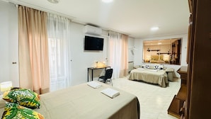 Ein Hotelzimmer mit Bett, Schreibtisch, Stuhl, Fernseher und Spiegel im Badezimmer.