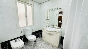 A bathroom with two toilets, a sink, a mirror, and a shower curtain.